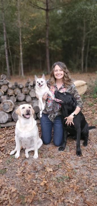 A woman poses with her three dogs.